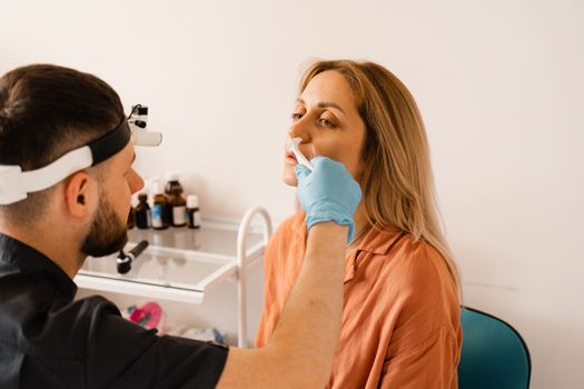 Rhinoscopy of woman nose. Consultation with doctor. Otolaryngologist examines girl nose before procedure of endoscopy of nose