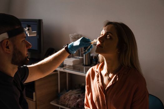 Rhinoscopy of woman nose. Consultation with doctor. Otolaryngologist examines girl nose before procedure of endoscopy of nose