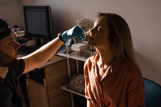 Rhinoscopy of woman nose. Consultation with doctor. Otolaryngologist examines girl nose before procedure of endoscopy of nose