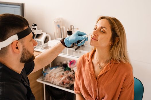 Rhinoscopy of woman nose. Consultation with doctor. Otolaryngologist examines girl nose before procedure of endoscopy of nose