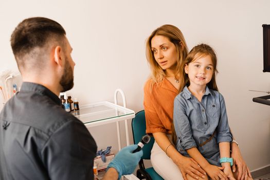 Woman and her child daughter visit ENT doctor. Consultation about endoscopy of nose for family with otolaryngologist in a medical clinic