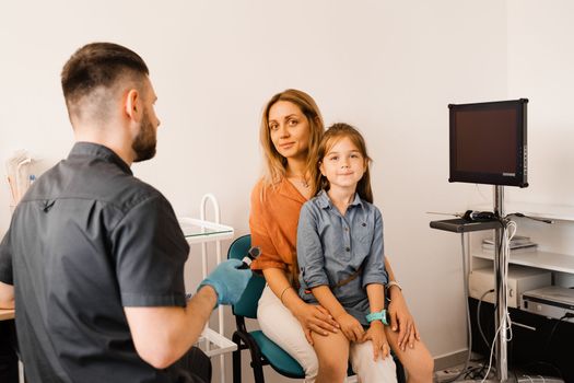 Woman and her child daughter visit ENT doctor. Consultation about endoscopy of nose for family with otolaryngologist in a medical clinic