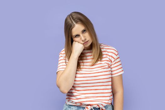 Unhappy depressed blond woman feeling bored with tedious conversation, feels disinterest and apathy, indifferent to life, lack of energy. Indoor studio shot isolated on purple background.