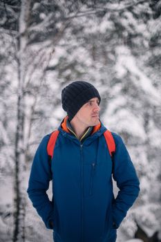 Man in winter jacket walking in snowy winter forest, snowy winter day