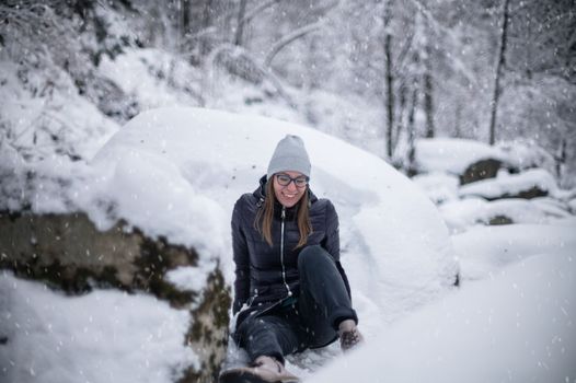 Woman in winter jacket walking in snowy winter forest, snowy winter day. Funny situation, woman fell down and laughs