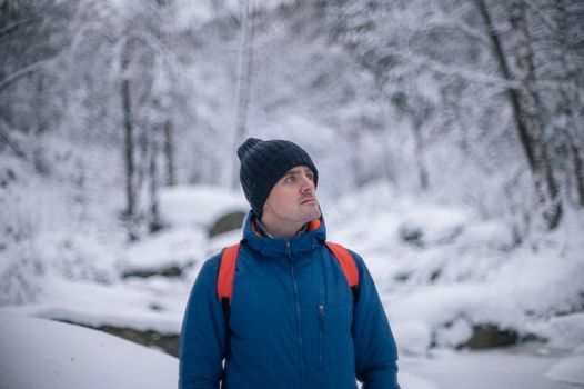 Man in winter jacket walking in snowy winter forest, snowy winter day