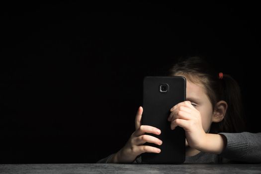 Kid gadget addiction and insomnia, psychological problems, black background, copy space.