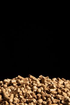 Heap of cat litter pellets on black background.