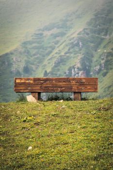 Wooden bench with a view of the mountains in a touristic hiking trail, copy space, vertical.