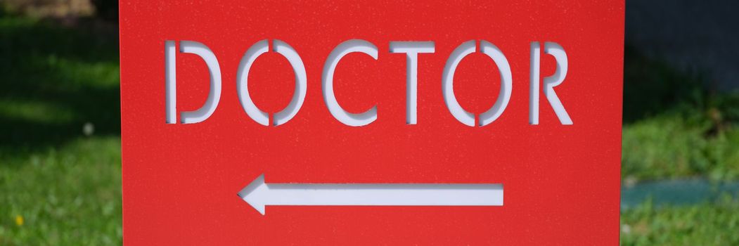 Red table with word doctor and arrow. Signpost for medical care concept