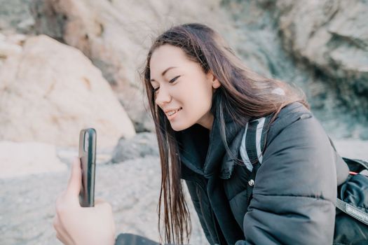 Portrait of cheerful female climber ascending a rock. The athlete girl trains in nature. Woman overcomes difficult climbing route.