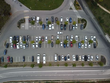 Busy large modern carpark with symmetrical roads rows of parking bays lots of symmetry and colours aerial view from drone up above looking down