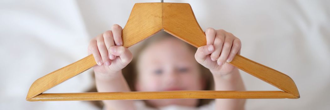 Child is holding wooden clothes hanger young.