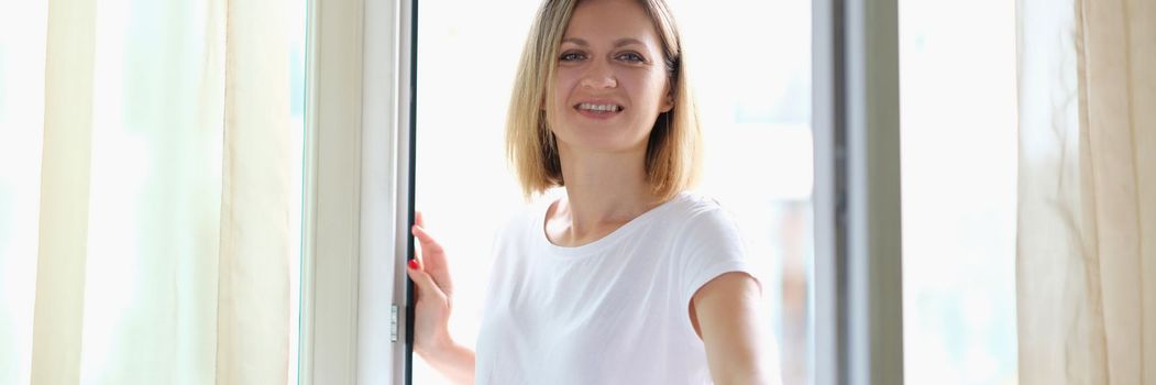 Beautiful smiling woman opens a glass door. Welcome and guest etiquette