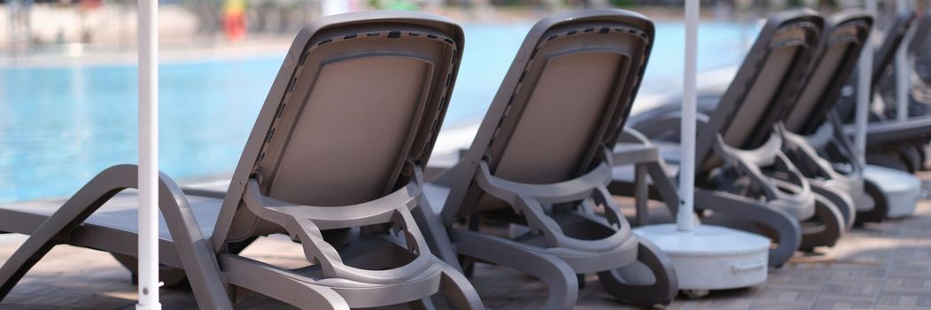 Empty sun loungers along pool in hotel in summer. Holidays at the resort concept