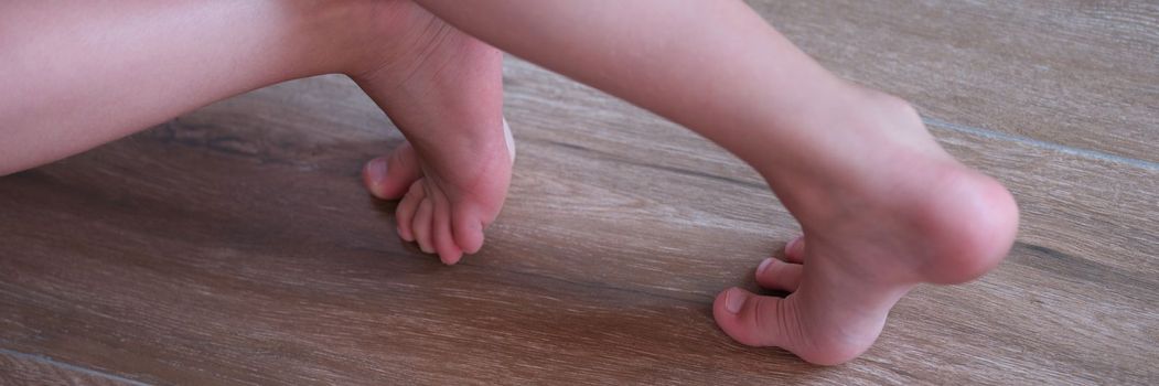 Children feet slide on wooden laminate at home. Wooden floors at home concept