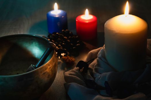 Tibetan singing bowl and colored candles with japa mala on a wooden table with copy space