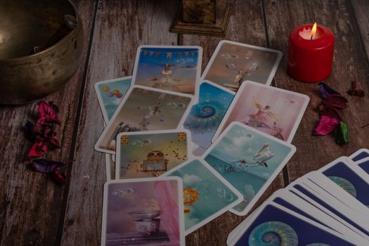 colorful tarot cards "oracle" lighted red candle, Tibetan bowl and incense burner on a wooden table and copy space