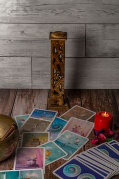 colorful tarot cards "oracle" lighted red candle, Tibetan bowl and incense burner on a wooden table and copy space
