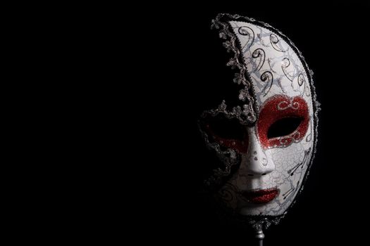 venetian carnival mask on black background partially blacked out with copy space