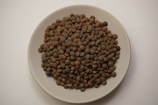 close-up of lentils on a white plate out of focus with white background
