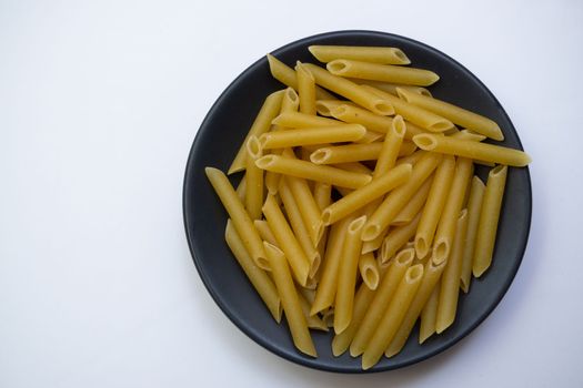 close-up of macaroni on a black plate on a white background and copy space
