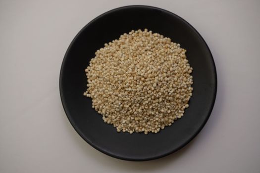 quinoa seeds on a black plate isolated on a white background