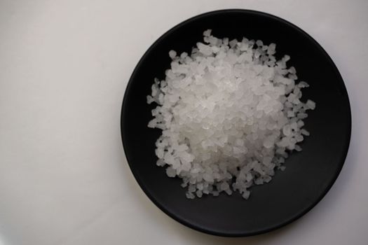 coarse salt on a black plate and white background with copy space