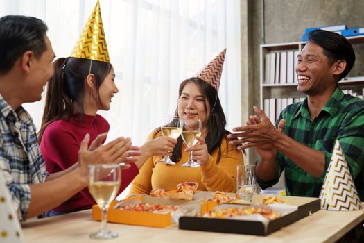 Friends at birthday party clinking glasses with champagne and pizza, enjoying Christmas vacation, pizza on the table. Holiday Party event