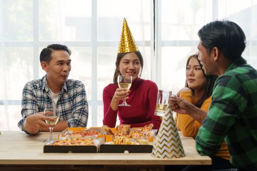 Friends at birthday party clinking glasses with champagne and pizza, enjoying Christmas vacation, pizza on the table. Holiday Party event