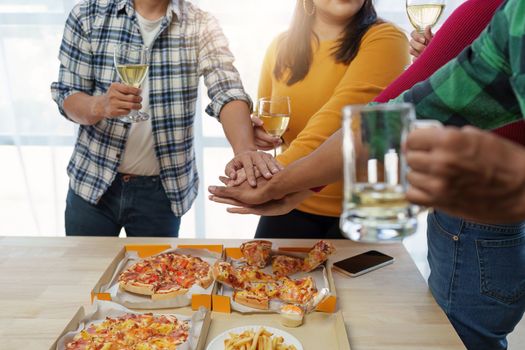 Friends at birthday party clinking glasses with champagne and pizza, enjoying Christmas vacation, pizza on the table. Holiday Party event