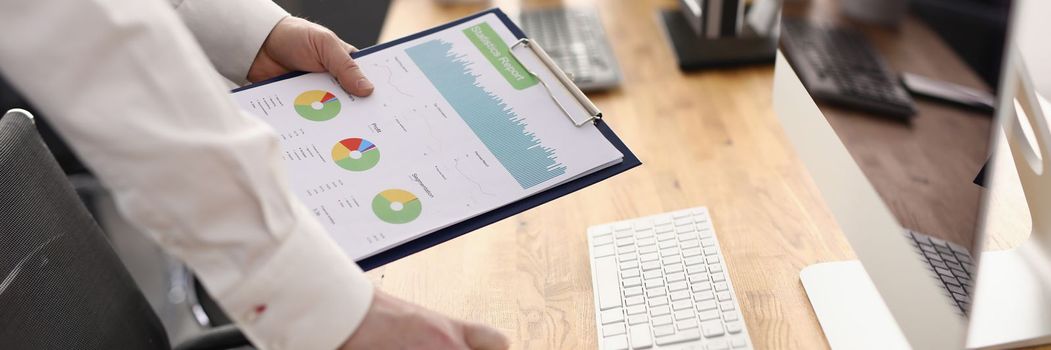 Analyst employee holds clipboard with graphs at workplace. Preparing statistics business indicators concept