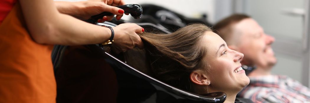 Beautiful happy smiling woman, professional hairdresser washes hair. Charming woman preparing her hair for new haircut concept