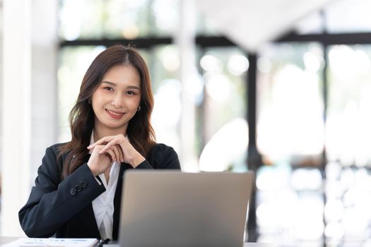 Charming Asian woman working at the office using a laptop Looking at the camera...