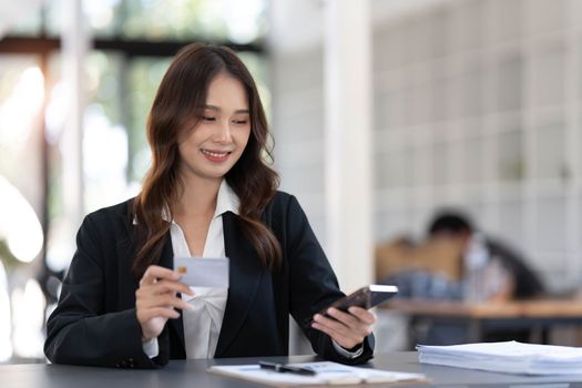 Young asian woman paying with credit card on smart phone at home office, Online payment concept