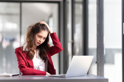 asian woman thinking hard concerned about online problem solution looking at laptop screen, worried serious asian businesswoman focused on solving difficult work computer task..