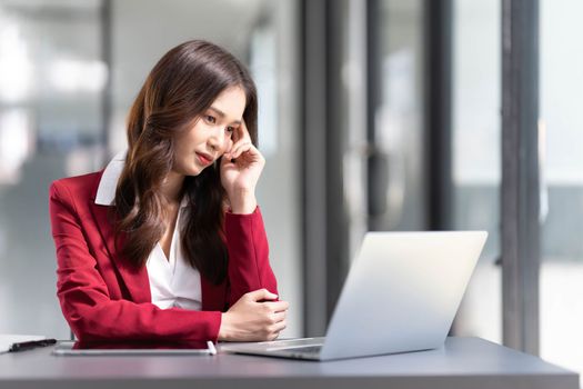 asian woman thinking hard concerned about online problem solution looking at laptop screen, worried serious asian businesswoman focused on solving difficult work computer task..