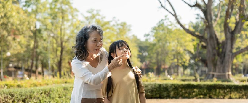 Happy granddaughter and her grandmother at summer park, family, leisure and people concept.