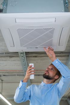 Caucasian bearded man repairing the air conditioner in the office