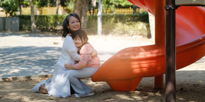 Asian Grandmother and Granddaughter hug together outdoor park. Hobbies and leisure, lifestyle, family life, happiness moment concept.