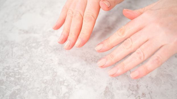 Woman finishing her manicure at home with simple manicure tools. Painting nails with fresh nail polish.