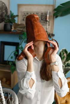 close-up photo of orange leather bag on a womans had. indoor photo. beautiful girl in a white blouse having fun with a handbag