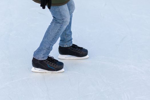 A pair of hockey skates with laces on frozen ice rink closeup. Ice skating or playing hockey in winter. ice and legs and copy space over ice background with marks from skating