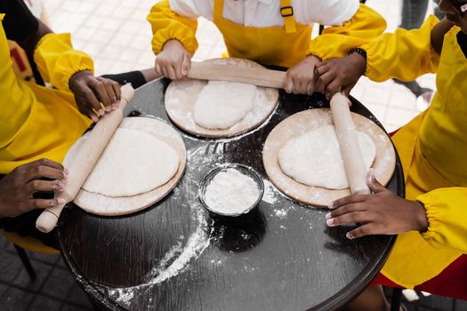 Multinational company of children cooks cooking dough close-up. Young cooks children cooking khachapuri