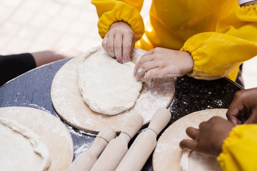 Multinational company of children cooks cooking dough close-up. Young cooks children cooking khachapuri