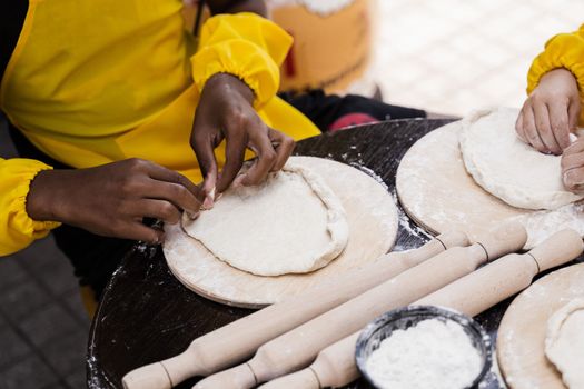 Multinational company of children cooks cooking dough close-up. Young cooks children cooking khachapuri