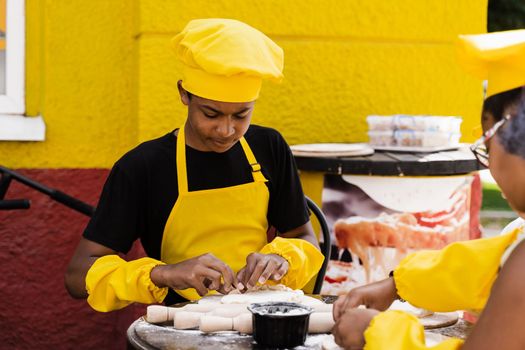 Black african teenager cook in chefs hat and yellow apron uniform cooking dough for bakery. Creative advertising for cafe or restaurant