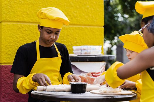 Childhood cook activity of multinational children of black african and caucasian kids. Happy company of multiethnic children cooking dough