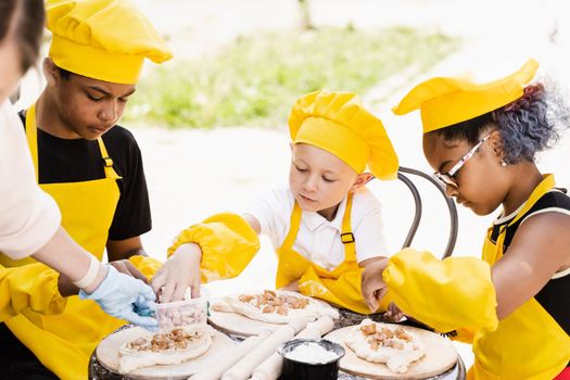 Happy company of multiethnic children cooking dough. Childhood cook activity of multinational children of black african and caucasian kids