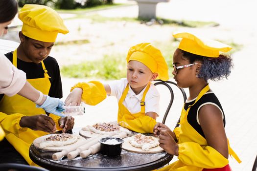 Childhood cook activity of multinational children of black african and caucasian kids. Happy company of multiethnic children cooking dough